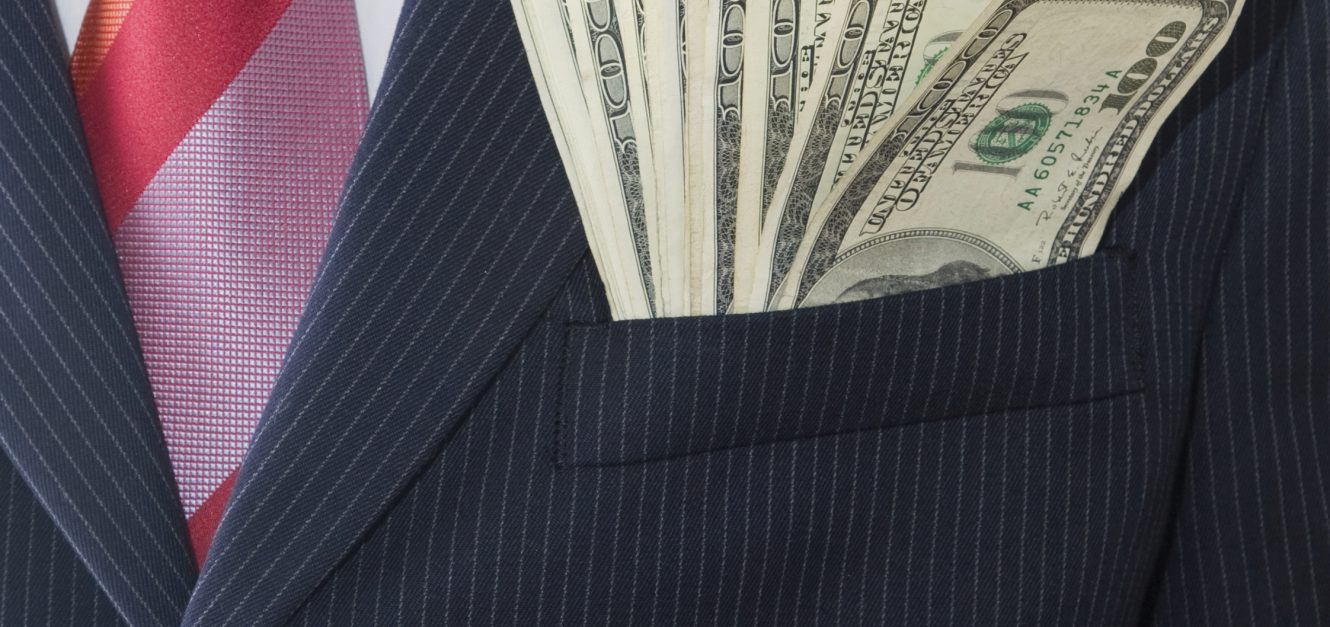 Business suit with 100 dollar bills coming out of pocket